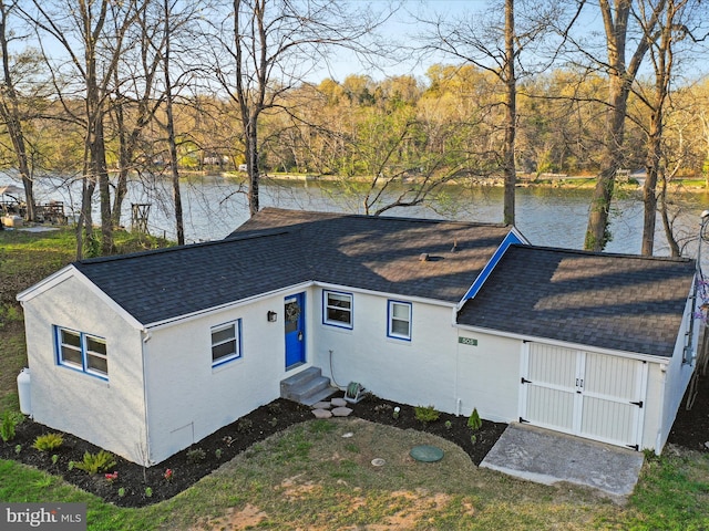 view of front of property with entry steps, a shingled roof, a water view, and stucco siding