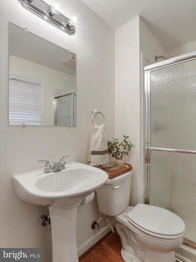 full bath featuring toilet, a stall shower, and wood finished floors