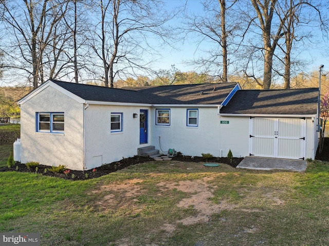 view of front of house featuring a front yard, roof with shingles, entry steps, and stucco siding