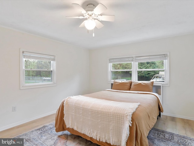 bedroom with multiple windows, baseboards, and wood finished floors