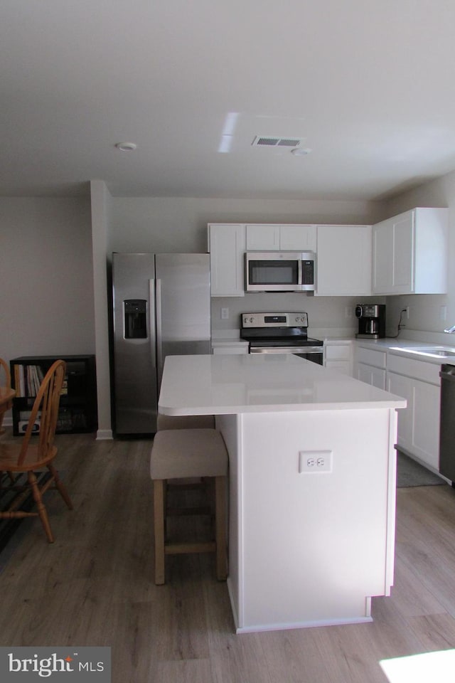 30155 Creekview Cir, Selbyville, DE 19975 - kitchen with a kitchen island, light wood finished floors, stainless steel appliances, visible vents, and white cabinets