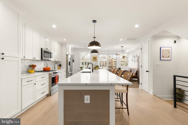 632 Rock Creek Church Rd NW Unit 2, Washington, DC 20010 - kitchen featuring stainless steel appliances, a kitchen breakfast bar, light wood-style floors, white cabinets, and recessed lighting