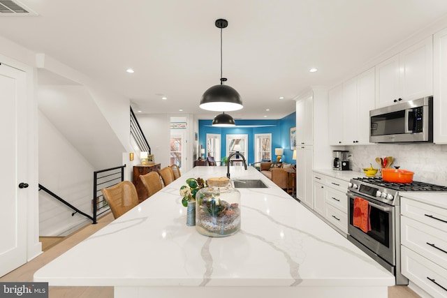 632 Rock Creek Church Rd NW Unit 2, Washington, DC 20010 - kitchen with appliances with stainless steel finishes, open floor plan, a spacious island, white cabinetry, and tasteful backsplash
