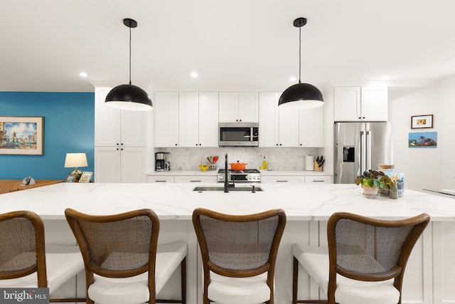 632 Rock Creek Church Rd NW Unit 2, Washington, DC 20010 - kitchen featuring stainless steel appliances, backsplash, white cabinetry, an island with sink, and hanging light fixtures