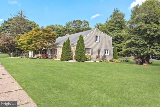view of side of home with a yard, roof with shingles, stone siding, and a chimney