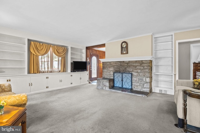 carpeted living room with crown molding, built in shelves, and a stone fireplace