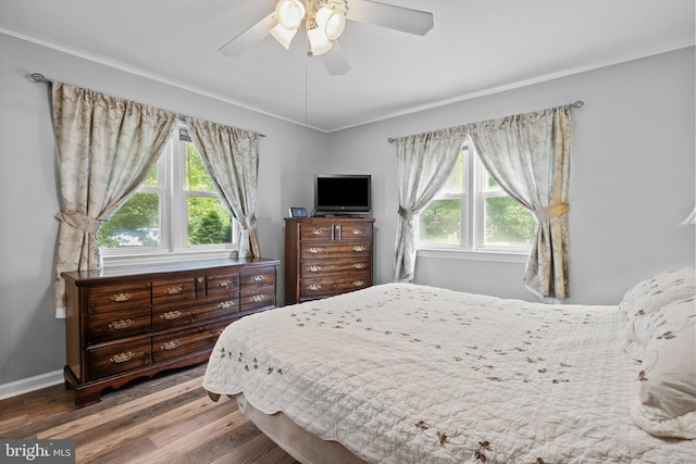 bedroom with crown molding, baseboards, a ceiling fan, and wood finished floors