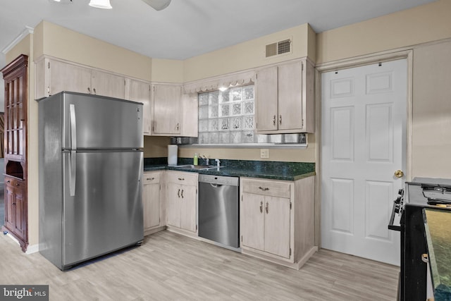 kitchen with visible vents, appliances with stainless steel finishes, a sink, dark countertops, and light wood finished floors