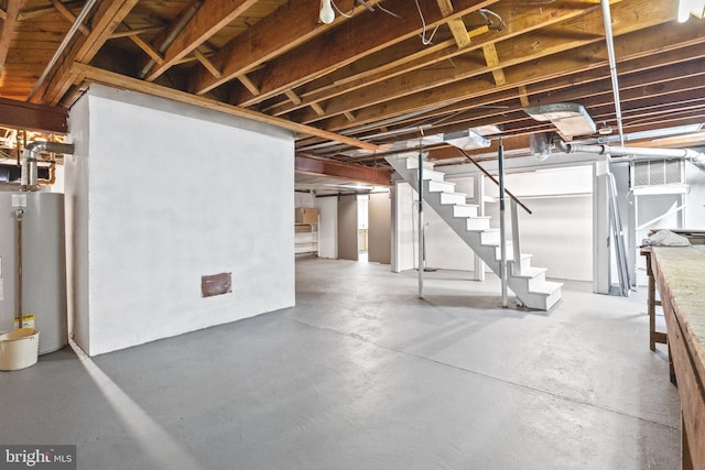 unfinished below grade area featuring gas water heater and stairway