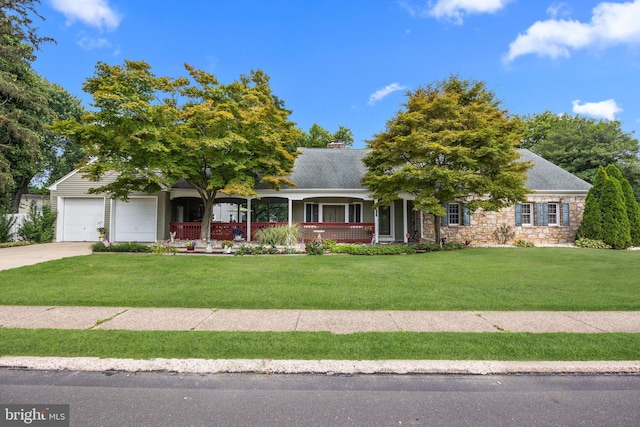 view of front of home featuring a front yard, an attached garage, stone siding, covered porch, and concrete driveway