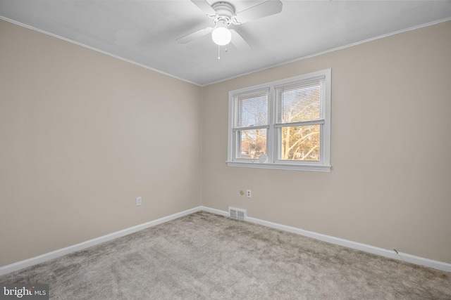 carpeted empty room featuring ornamental molding, baseboards, and a ceiling fan