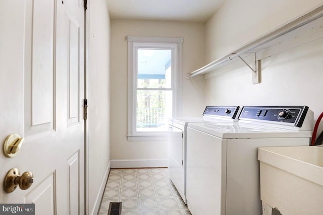 laundry area with washer and dryer, light flooring, and baseboards