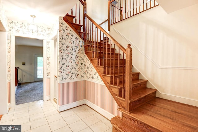 staircase featuring wallpapered walls, tile patterned floors, and baseboards