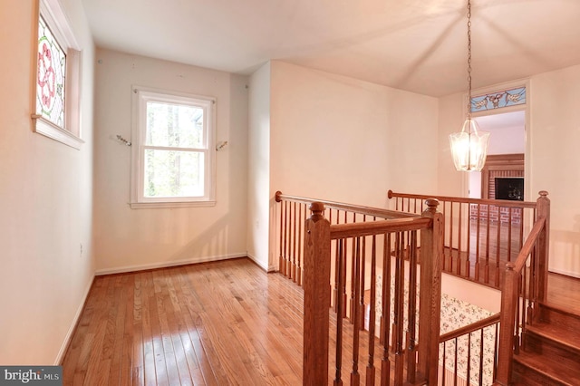 bonus room with wood-type flooring, baseboards, and a chandelier