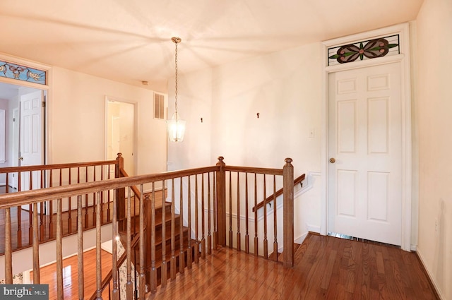 hallway featuring an upstairs landing, wood finished floors, and baseboards
