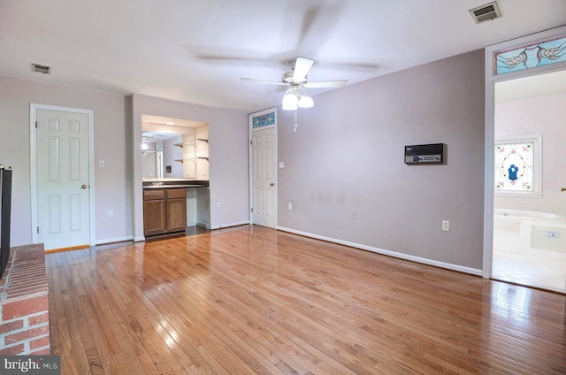 unfurnished living room with a ceiling fan, light wood-type flooring, and baseboards