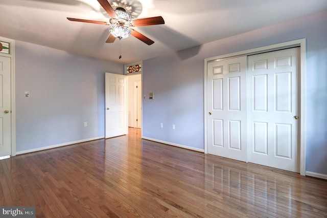 unfurnished bedroom with baseboards, wood finished floors, a closet, and a ceiling fan