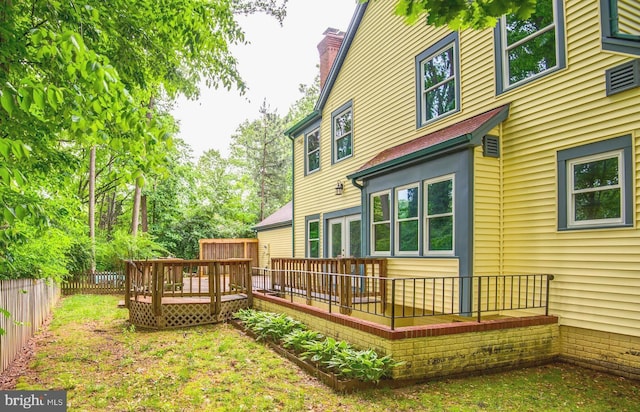 back of property with a wooden deck, a fenced backyard, and a chimney