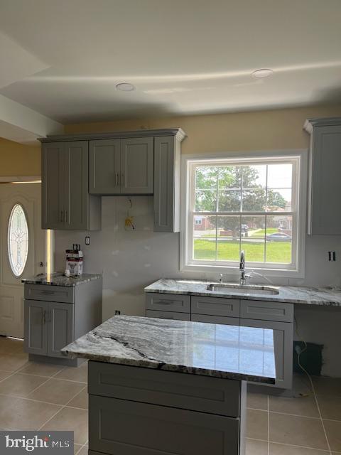 628 W 2nd St, Florence, NJ 08518 - kitchen with gray cabinets, light tile patterned floors, light stone counters, and plenty of natural light