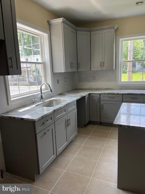 628 W 2nd St, Florence, NJ 08518 - kitchen featuring light stone countertops, gray cabinetry, and light tile patterned floors