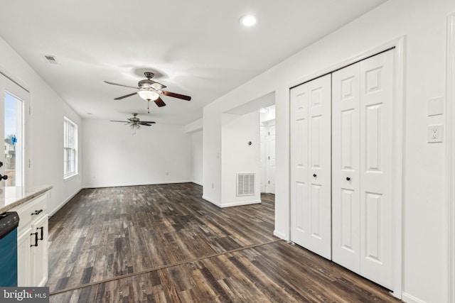 unfurnished living room featuring a ceiling fan, dark wood-style flooring, baseboards, and visible vents