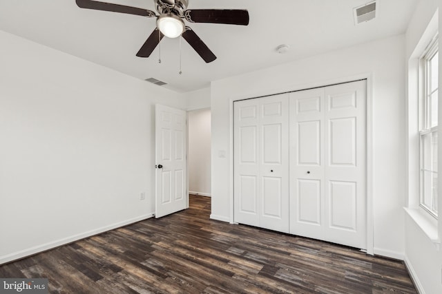 unfurnished bedroom featuring baseboards, dark wood-style flooring, and visible vents