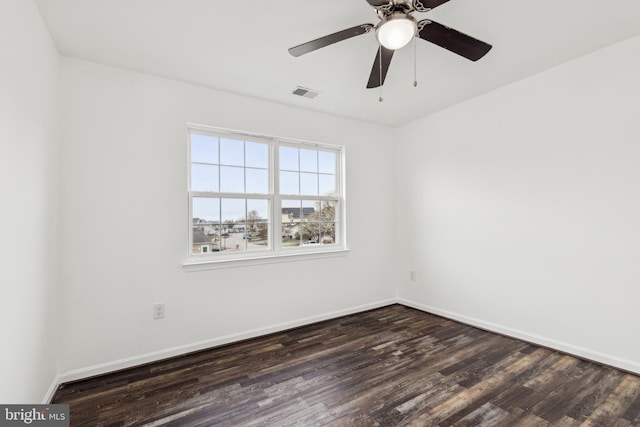 spare room featuring baseboards, ceiling fan, visible vents, and dark wood finished floors