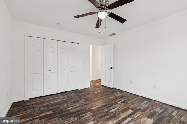 unfurnished bedroom featuring a closet, dark wood finished floors, baseboards, visible vents, and ceiling fan
