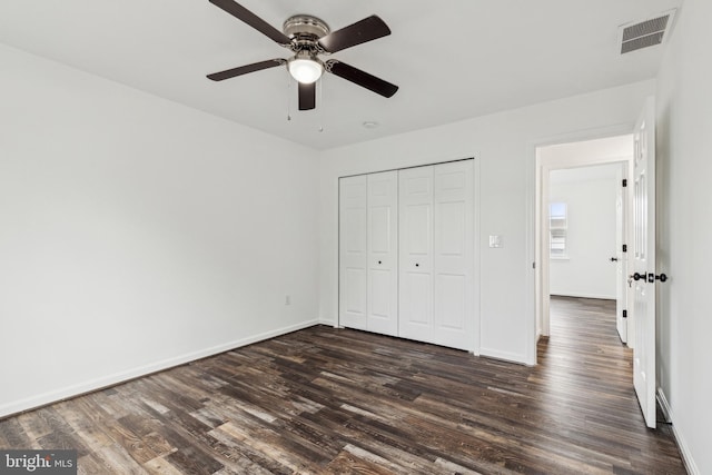 unfurnished bedroom featuring baseboards, visible vents, a closet, and dark wood-type flooring