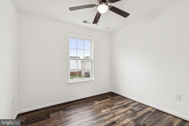 spare room featuring baseboards, dark wood-style floors, visible vents, and ceiling fan