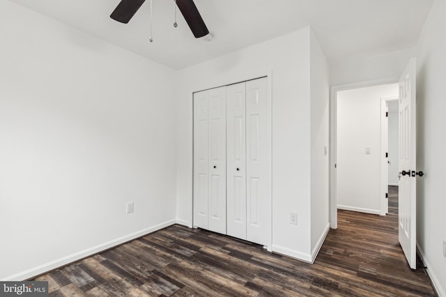 unfurnished bedroom with baseboards, a closet, dark wood-type flooring, and a ceiling fan