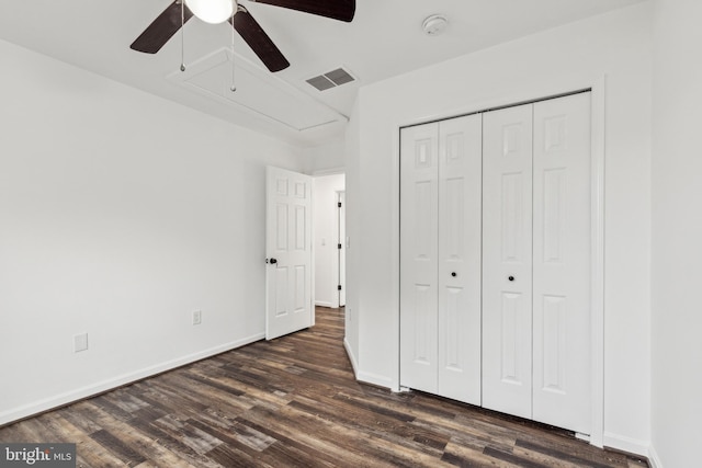 unfurnished bedroom featuring attic access, dark wood-style flooring, baseboards, visible vents, and a closet