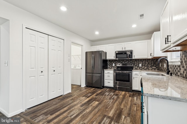 kitchen featuring dark wood-style flooring, stainless steel appliances, a sink, light stone counters, and white cabinets