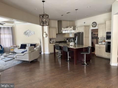 2042 Drovers Ln, Cooksville, MD 21723 - kitchen featuring appliances with stainless steel finishes, wall chimney range hood, open floor plan, a breakfast bar area, and dark wood-style floors