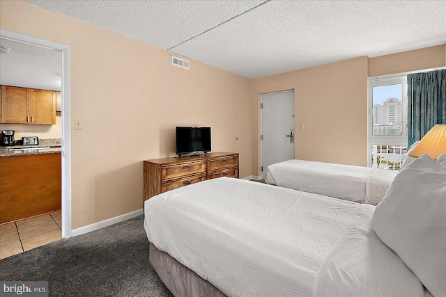 carpeted bedroom with baseboards, visible vents, tile patterned flooring, and a textured ceiling