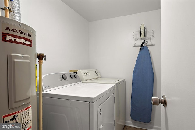 washroom with washing machine and clothes dryer, electric water heater, and laundry area