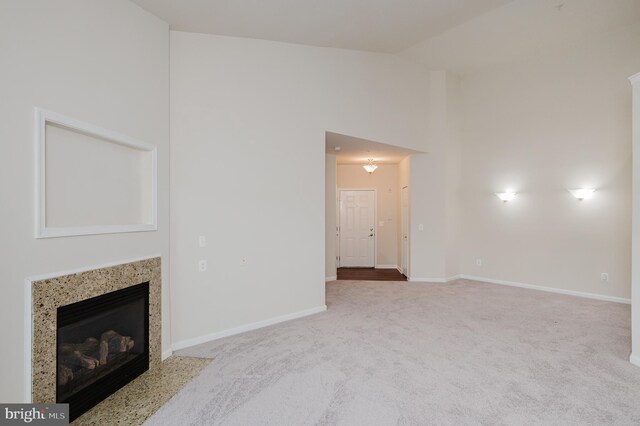 5207 Wyndholme Cir Unit 402, Baltimore, MD 21229 - unfurnished living room with a high end fireplace, vaulted ceiling, baseboards, and carpet floors