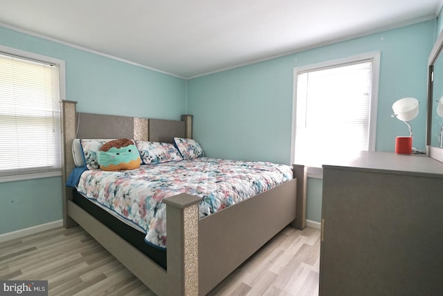 bedroom featuring baseboards, wood finished floors, and crown molding