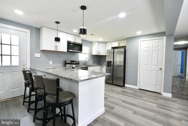 kitchen with white cabinetry, light wood-style flooring, stainless steel appliances, and a peninsula