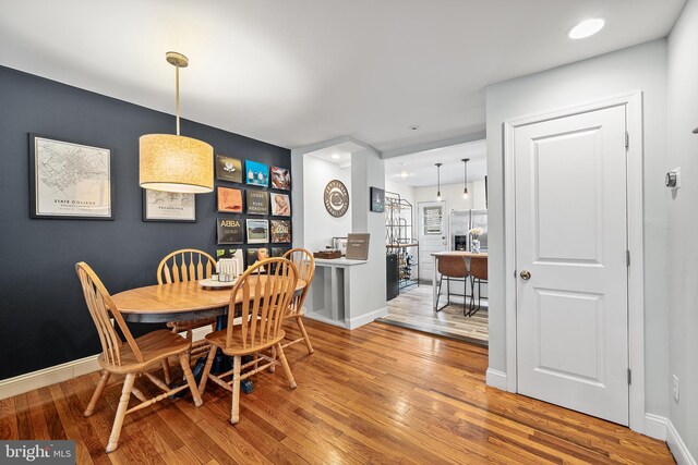 dining area with baseboards, wood finished floors, and recessed lighting