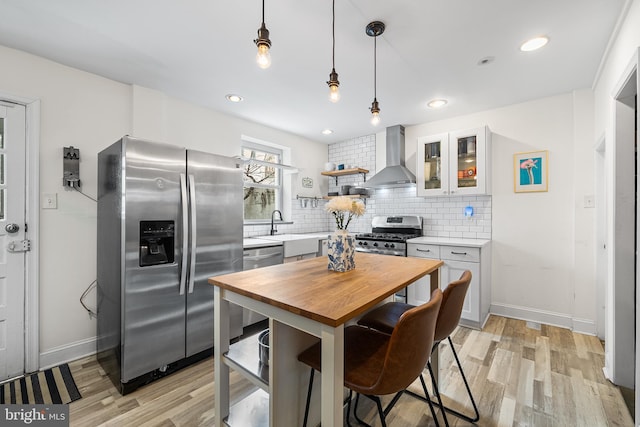 kitchen featuring a sink, wall chimney exhaust hood, stainless steel appliances, wood counters, and decorative backsplash