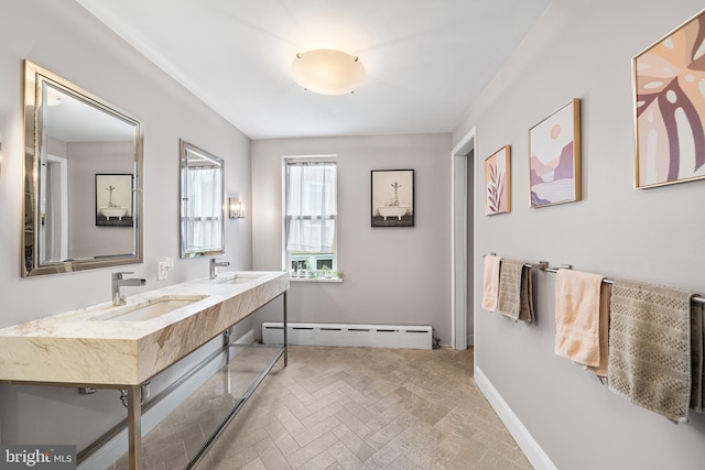 bathroom featuring baseboards, double vanity, a sink, and baseboard heating