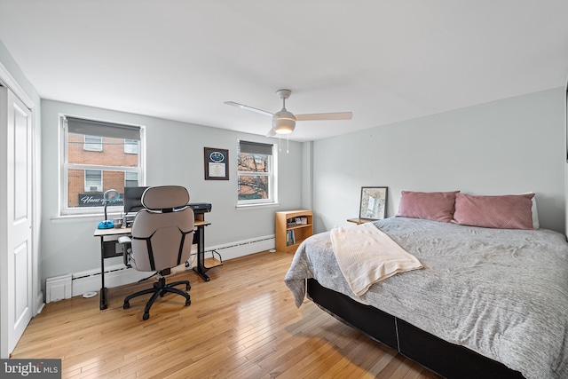 bedroom with wood-type flooring, multiple windows, and a baseboard heating unit