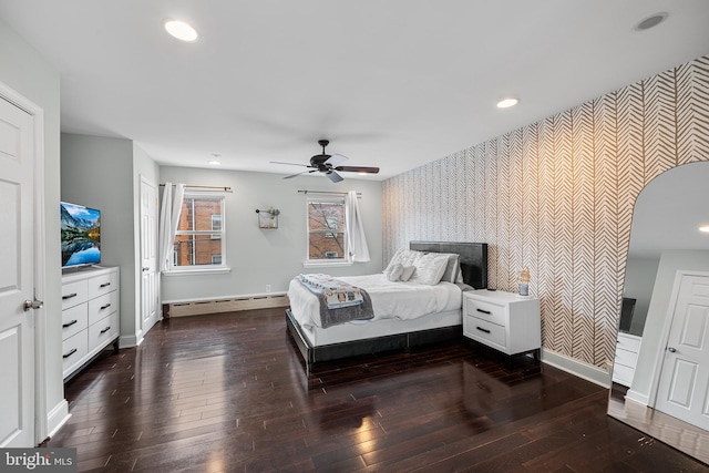 bedroom with wood-type flooring, wallpapered walls, a baseboard heating unit, and an accent wall