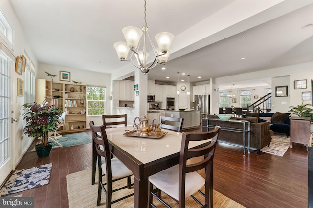 dining space featuring an inviting chandelier, dark wood finished floors, and stairs