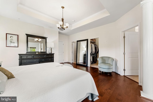 bedroom featuring a chandelier, wood finished floors, crown molding, and a raised ceiling