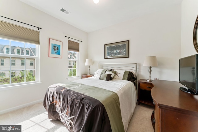 bedroom featuring visible vents, multiple windows, light colored carpet, and baseboards
