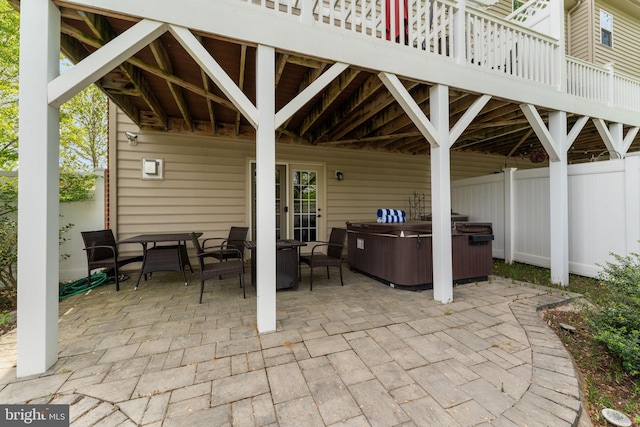 view of patio with fence, outdoor dining area, and a hot tub