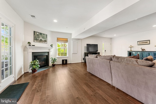 living area with baseboards, recessed lighting, dark wood-type flooring, and a glass covered fireplace