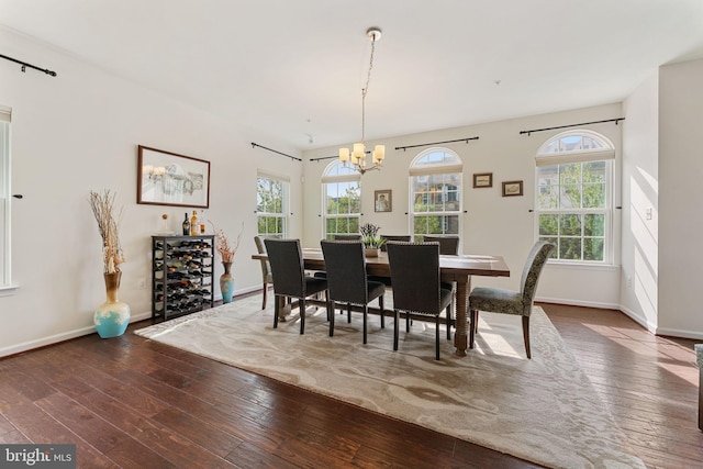 dining space with hardwood / wood-style floors, a chandelier, and baseboards